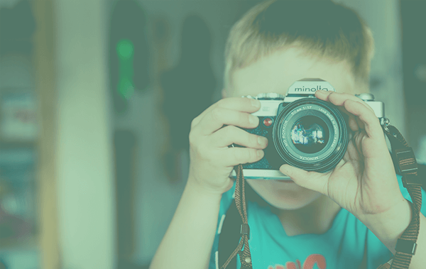 jongen met een fotocamera voor zijn gezicht