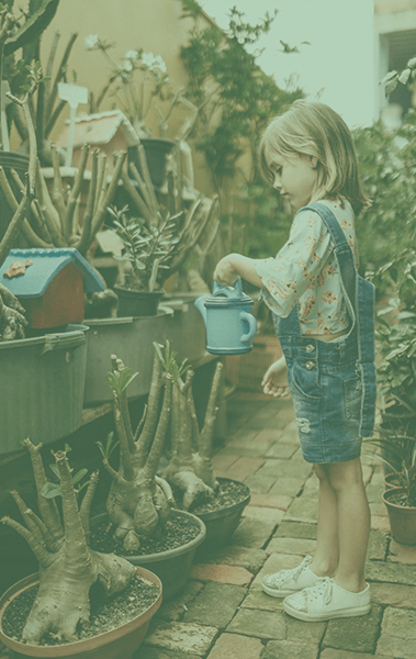 meisje dat buiten met een gieter planten water geeft